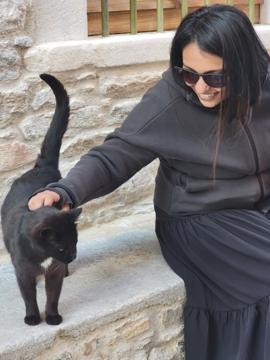 Nandini Mathan smiling and petting a black cat.